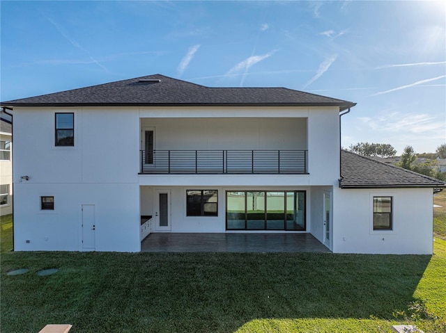 rear view of property with a lawn, a balcony, and a patio