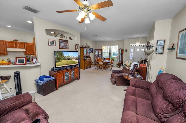 carpeted living room with ceiling fan with notable chandelier