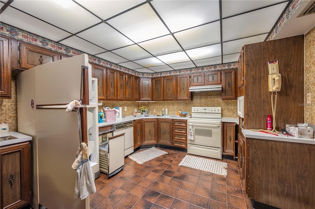 kitchen featuring a paneled ceiling, sink, and white appliances