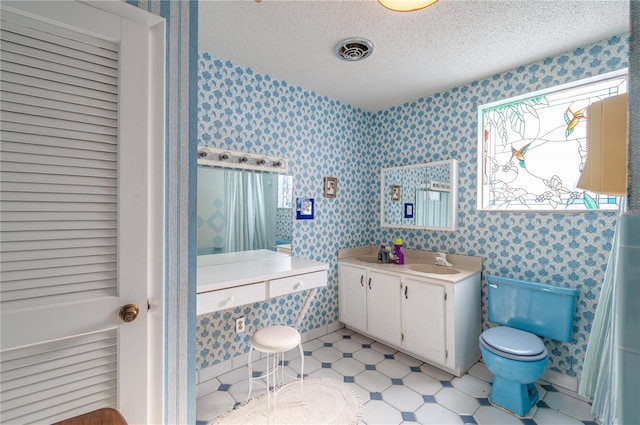 bathroom with vanity, toilet, and a textured ceiling