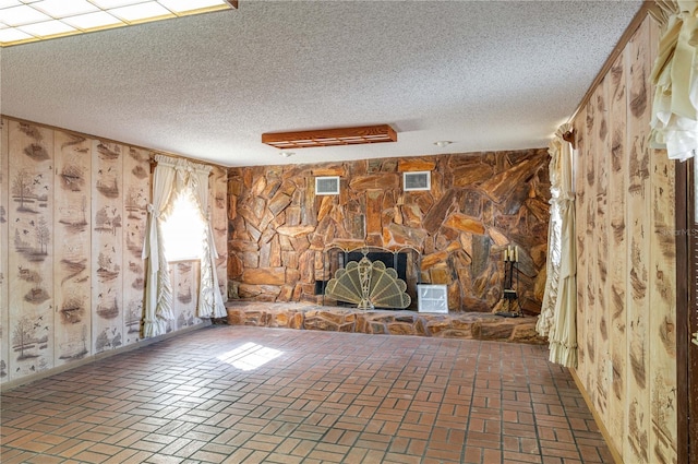 unfurnished living room featuring a stone fireplace and a textured ceiling