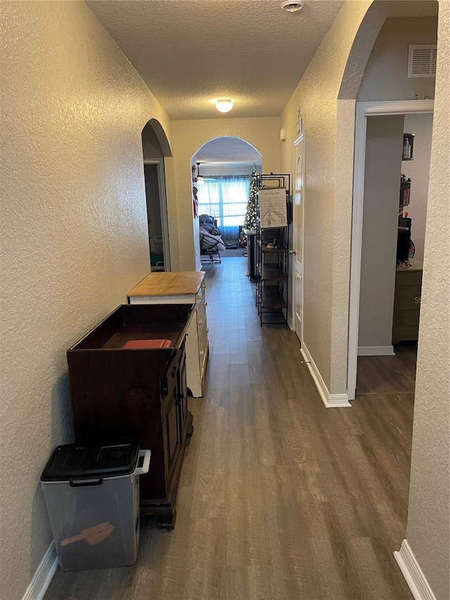 hallway with a textured ceiling and dark hardwood / wood-style flooring