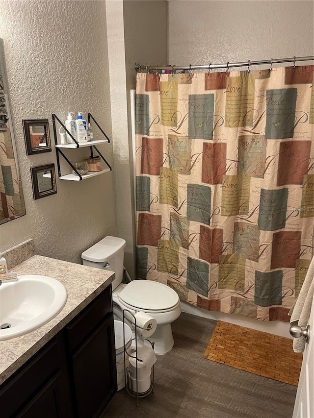 bathroom with hardwood / wood-style floors, vanity, toilet, and walk in shower