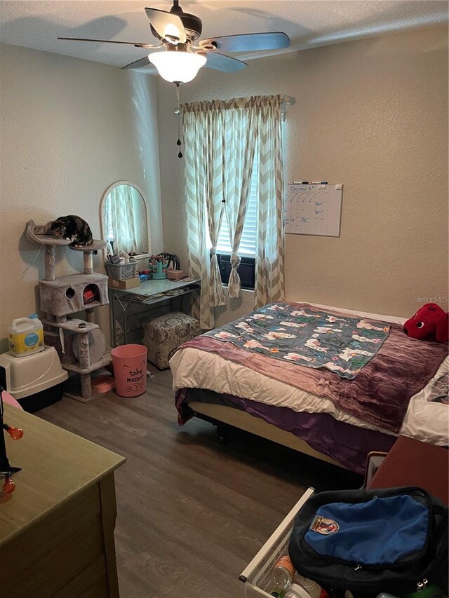 bedroom featuring ceiling fan, wood-type flooring, and a textured ceiling