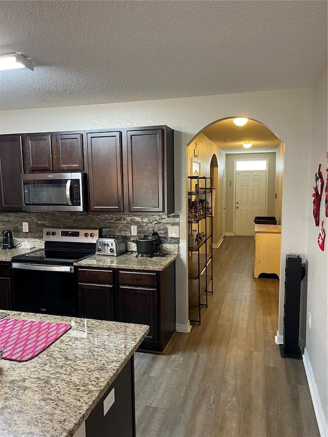 kitchen with hardwood / wood-style flooring, backsplash, stainless steel appliances, and a textured ceiling