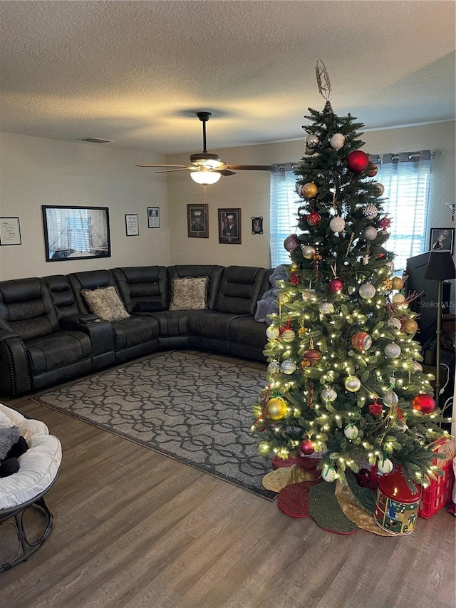 living room with ceiling fan, wood-type flooring, and a textured ceiling