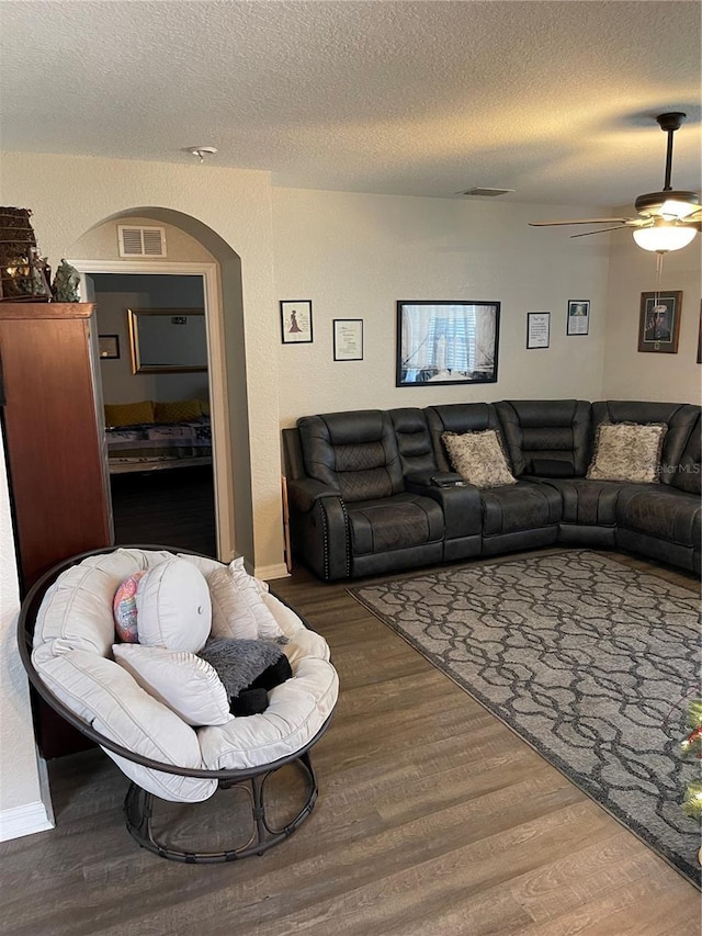 living room with ceiling fan, a textured ceiling, and hardwood / wood-style flooring