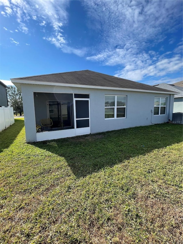 rear view of house featuring a sunroom, a yard, and cooling unit