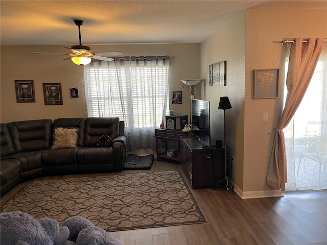 living room with a textured wall, ceiling fan, a wealth of natural light, and wood finished floors