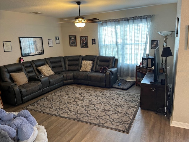 living area with visible vents, a ceiling fan, baseboards, and wood finished floors