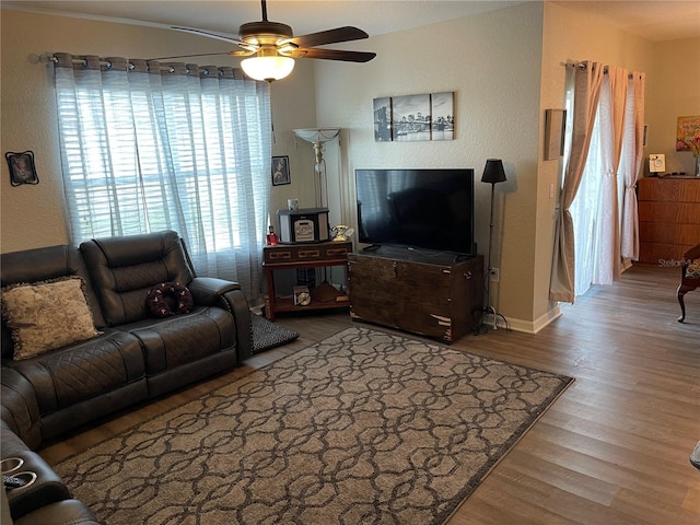 living area with baseboards, a ceiling fan, and wood finished floors