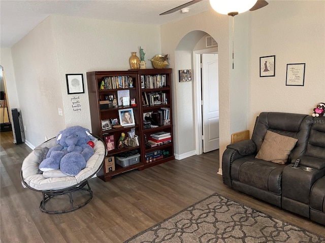 living room with ceiling fan, arched walkways, baseboards, wood finished floors, and visible vents