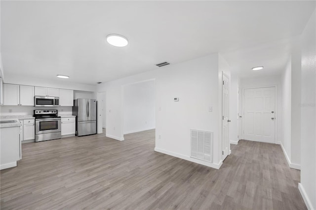 kitchen with white cabinets, sink, stainless steel appliances, and light hardwood / wood-style flooring