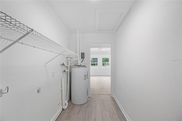 laundry room featuring water heater and light wood-type flooring