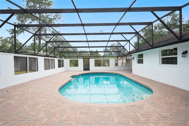 view of pool with glass enclosure and a patio area