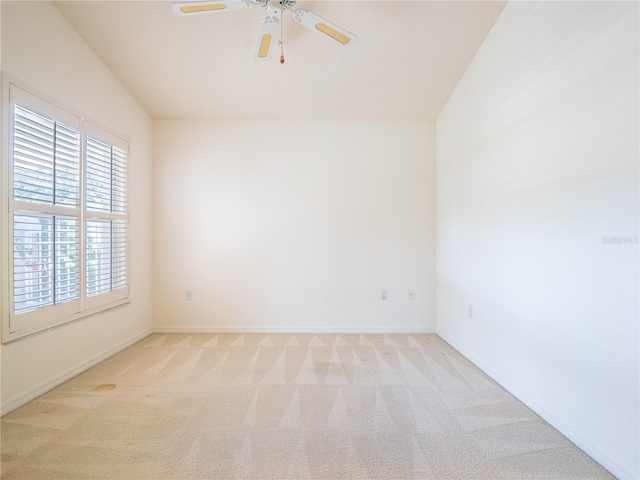 spare room featuring ceiling fan, light colored carpet, and vaulted ceiling