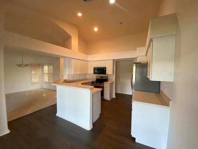 kitchen featuring kitchen peninsula, appliances with stainless steel finishes, dark hardwood / wood-style flooring, high vaulted ceiling, and white cabinetry