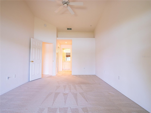 carpeted spare room with ceiling fan and high vaulted ceiling