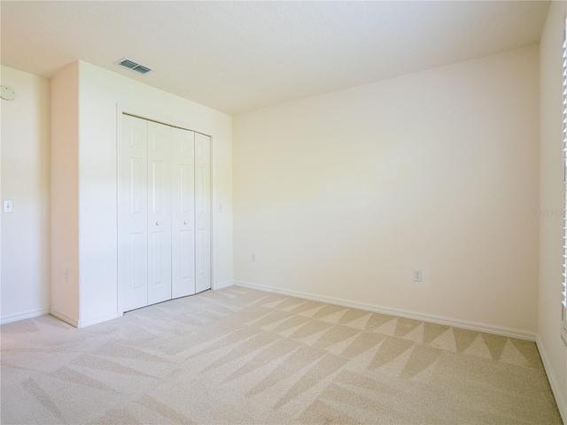 unfurnished bedroom featuring light colored carpet and a closet