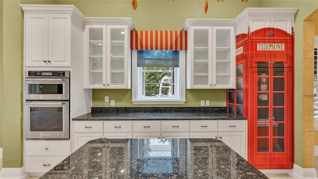 kitchen featuring white cabinets, double oven, and dark stone counters