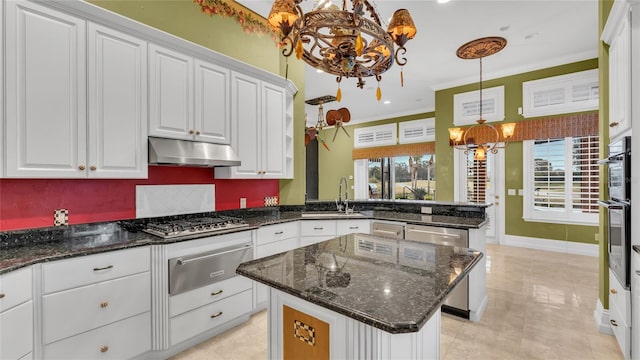 kitchen with an inviting chandelier, a center island, hanging light fixtures, appliances with stainless steel finishes, and white cabinets