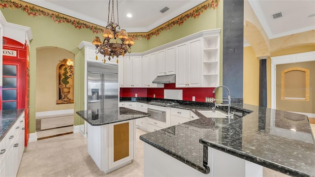 kitchen featuring white cabinetry, dark stone countertops, appliances with stainless steel finishes, kitchen peninsula, and pendant lighting