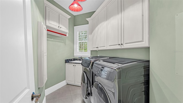 clothes washing area with cabinets, washing machine and clothes dryer, and light tile patterned floors