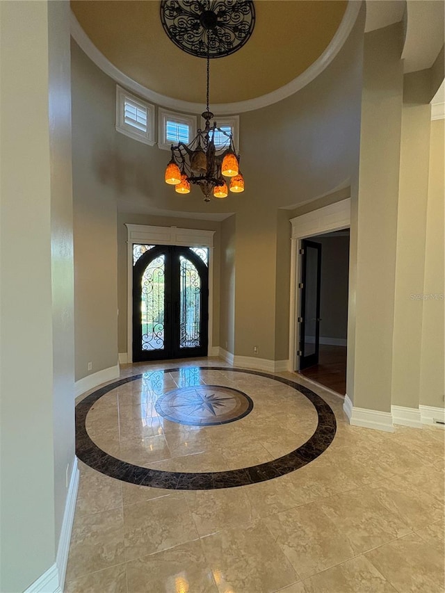 entryway with a towering ceiling, french doors, and a chandelier