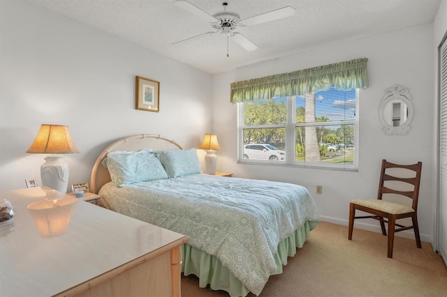 bedroom with a textured ceiling, ceiling fan, and light carpet