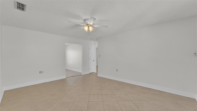 tiled empty room with ceiling fan and a textured ceiling