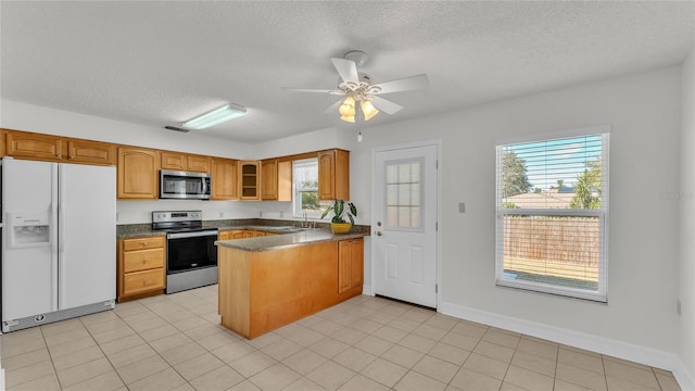 kitchen featuring ceiling fan, kitchen peninsula, a textured ceiling, light tile patterned floors, and appliances with stainless steel finishes