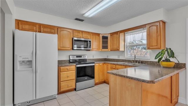 kitchen with kitchen peninsula, appliances with stainless steel finishes, a textured ceiling, sink, and light tile patterned floors