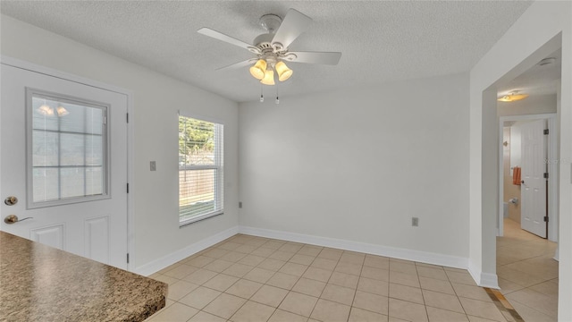 interior space with light tile patterned floors, a textured ceiling, and ceiling fan