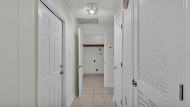 corridor featuring light tile patterned flooring and a textured ceiling