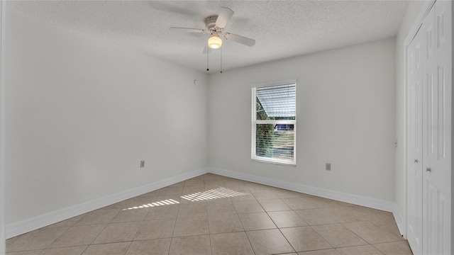 unfurnished room with ceiling fan, light tile patterned floors, and a textured ceiling