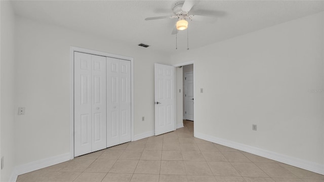 unfurnished bedroom featuring light tile patterned floors, a textured ceiling, a closet, and ceiling fan