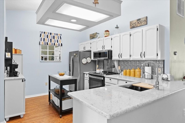 kitchen featuring kitchen peninsula, decorative backsplash, light hardwood / wood-style floors, white cabinetry, and stainless steel appliances