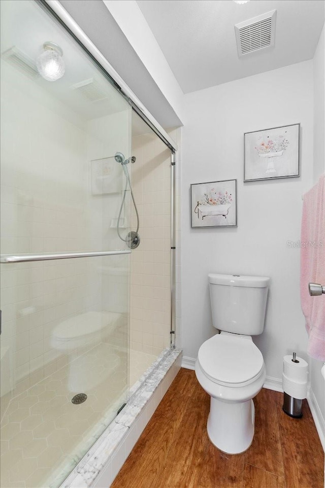 bathroom with a shower with door, wood-type flooring, and toilet