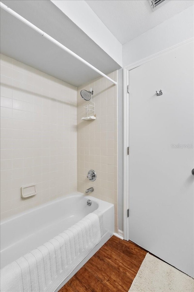 bathroom with wood-type flooring and tiled shower / bath