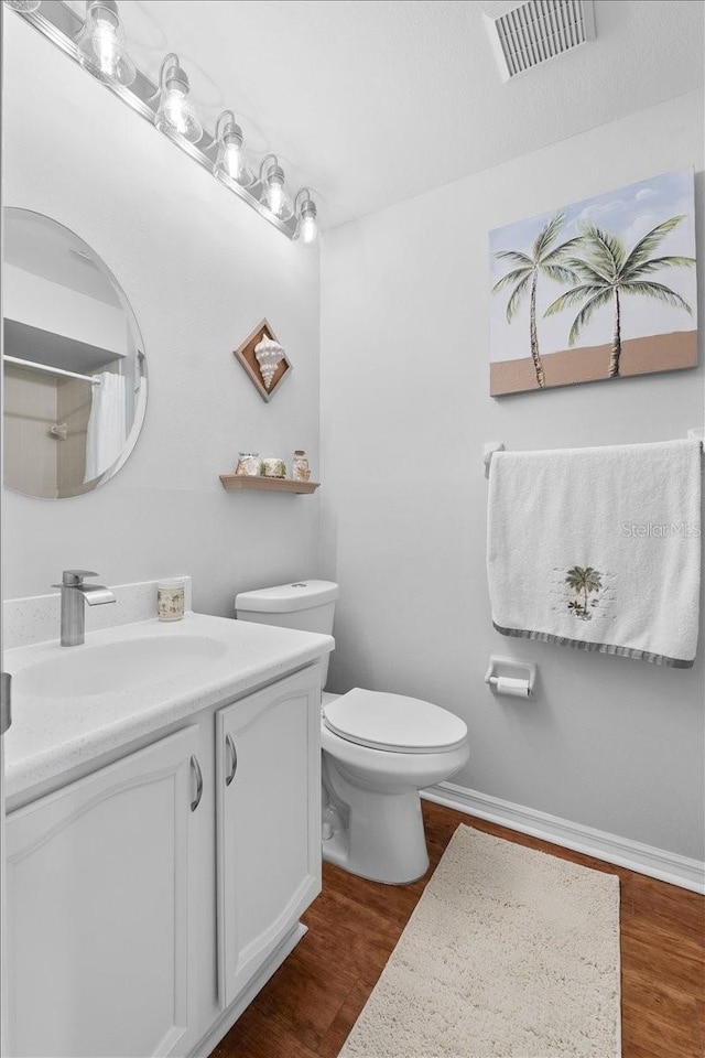 bathroom featuring walk in shower, vanity, wood-type flooring, and toilet