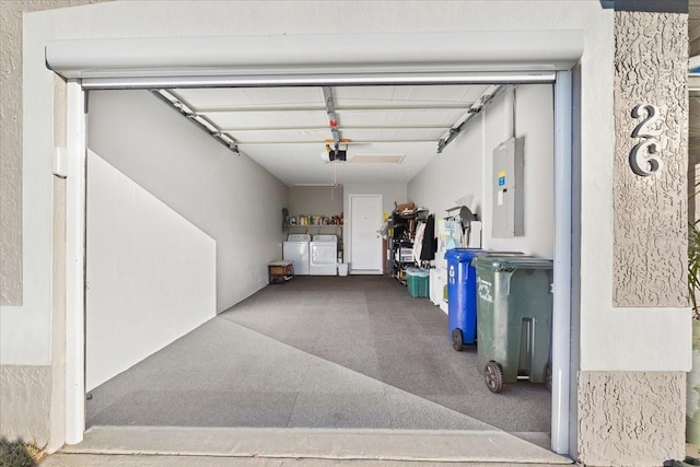 garage featuring independent washer and dryer, electric panel, and a garage door opener