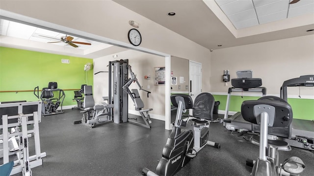 exercise room with a tray ceiling and ceiling fan