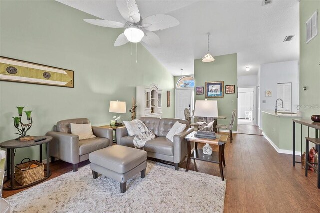 living room featuring ceiling fan, wood-type flooring, sink, and high vaulted ceiling