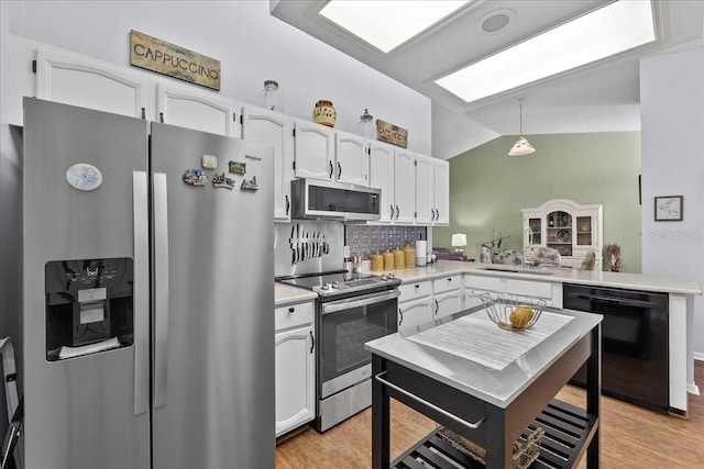 kitchen with stainless steel appliances, vaulted ceiling, sink, white cabinetry, and hanging light fixtures