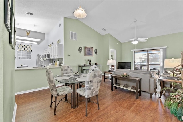 dining area featuring a textured ceiling, hardwood / wood-style flooring, ceiling fan, and lofted ceiling