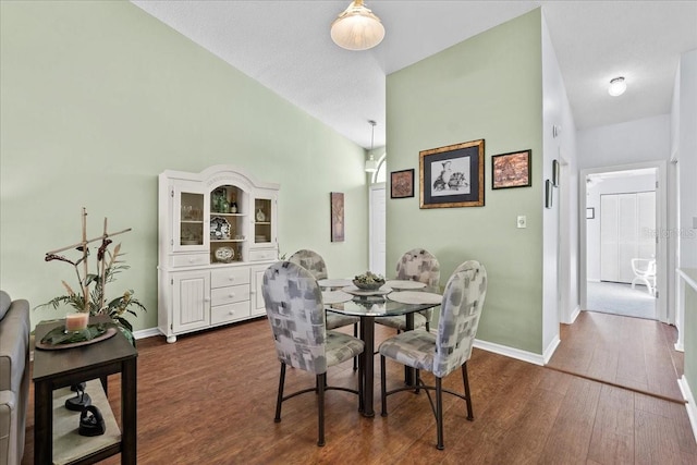 dining room with high vaulted ceiling and dark wood-type flooring