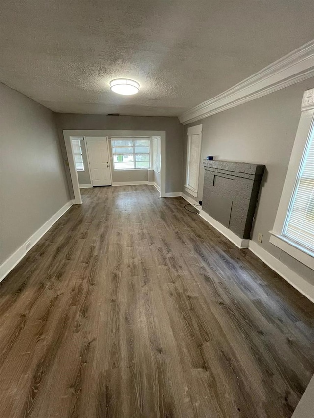 unfurnished living room featuring a textured ceiling, ornamental molding, and dark wood-type flooring