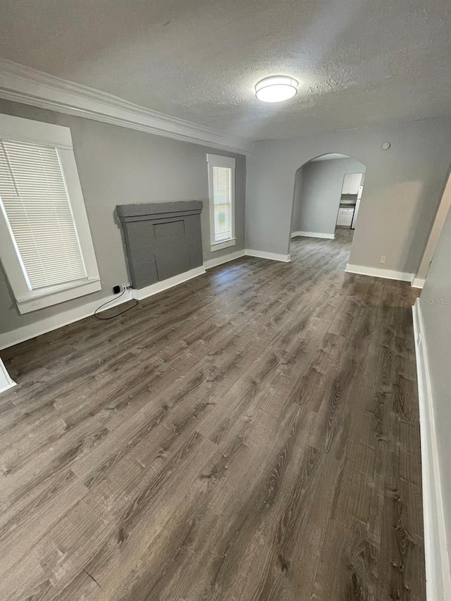 interior space featuring a textured ceiling, crown molding, and dark wood-type flooring