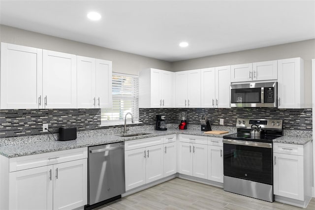 kitchen featuring backsplash, white cabinetry, sink, and appliances with stainless steel finishes