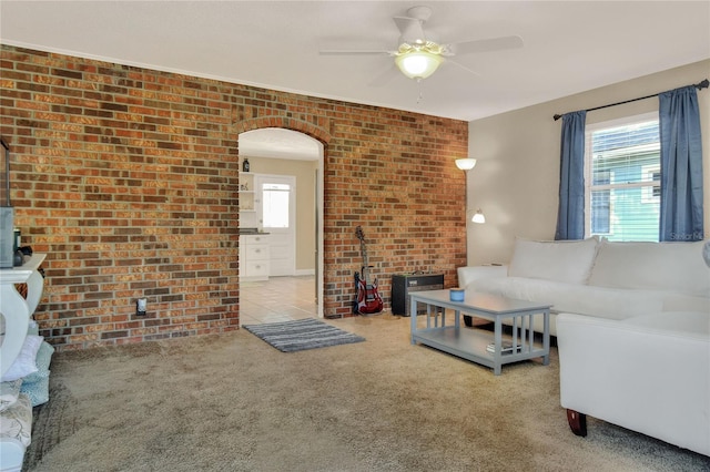 carpeted living room featuring ceiling fan and brick wall